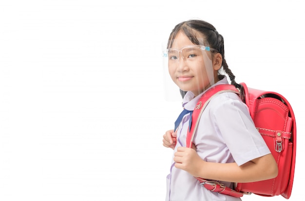 Aluna bonito usando escudo facial e carrega a mochila para ir à escola isolada