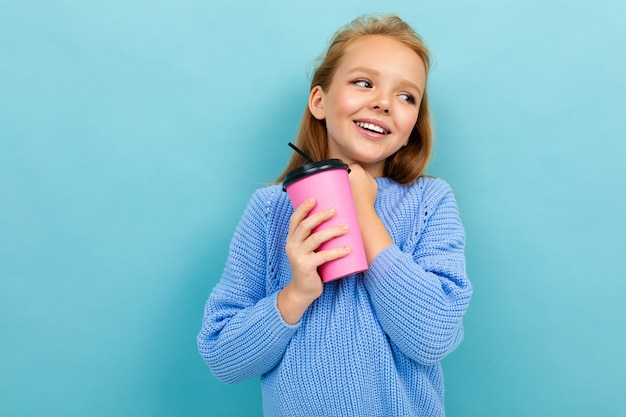 Aluna carismática alegre ri de um azul com um copo de café nas mãos