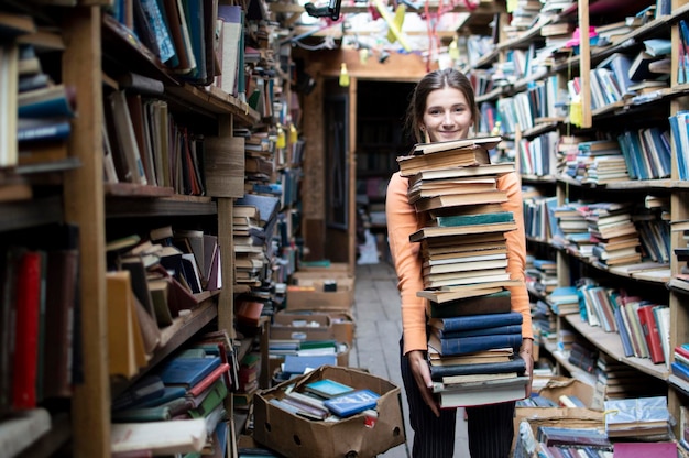 Aluna carrega uma grande pilha de livros na preparação da biblioteca para o conhecimento do estudo é conceito de poder