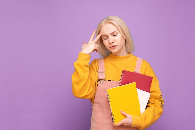 Aluna com livros e cadernos nas mãos fica de olhos fechados