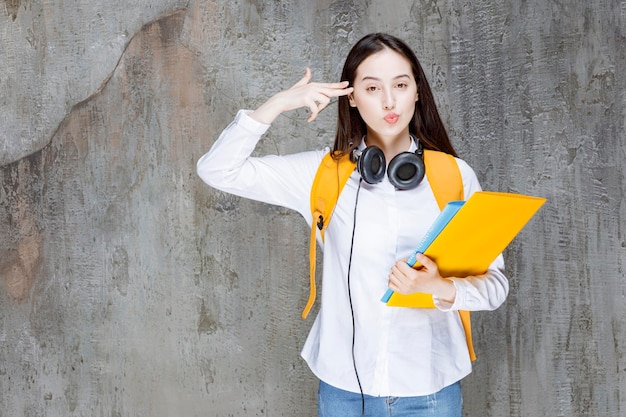 Aluna com mochila e fones de ouvido apontando para a cabeça dela. foto de alta qualidade