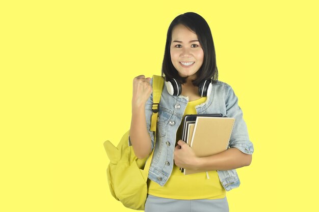 Aluna com mochila e segurando cadernos mostrando um gesto de sim. conceito de educação