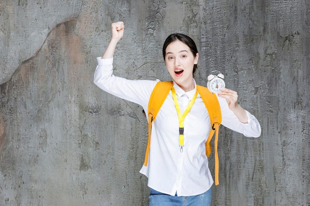 Aluna com mochila segurando o relógio. foto de alta qualidade