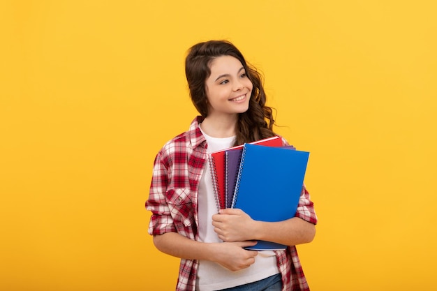 Aluna com notebook de volta à escola adolescente pronta para estudar criança alegre de infância feliz vai fazer lição de casa com livros sorrindo educação estudantil e conhecimento colegial