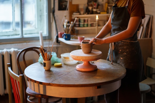 Aluna da aula de cerâmica moldando o vaso no estúdio mulher artesã preparando cerâmica para a venda no feriado