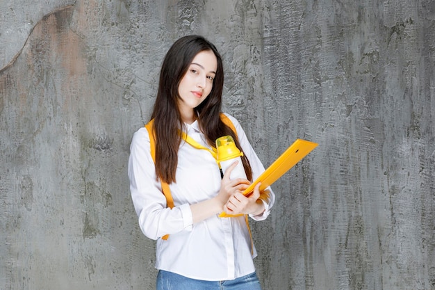 Aluna de camisa branca segurando livros. Foto de alta qualidade