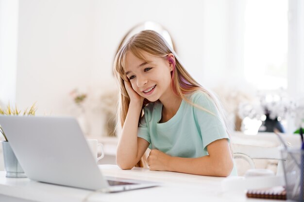 Aluna de menina feliz usando o laptop em casa