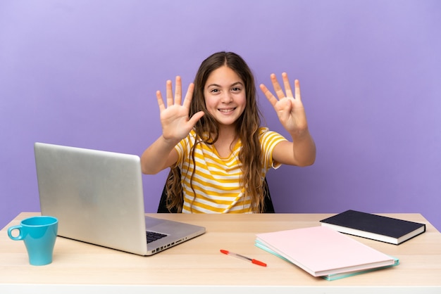 Aluna em um local de trabalho com um laptop isolado no fundo roxo, contando nove com os dedos