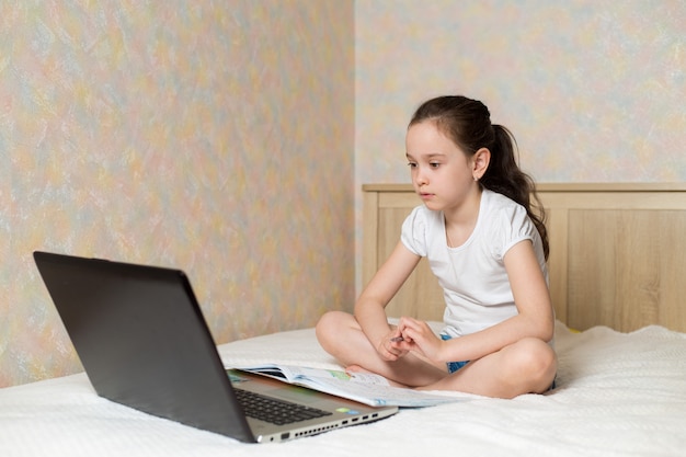 Foto aluna estudando em casa com o notebook digital tablet laptop e fazendo lição de casa na escola com livros de treinamento