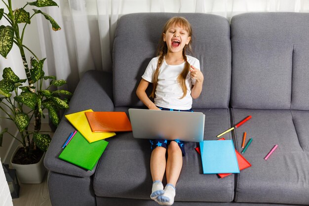 Aluna estudando em casa usando o laptop. Escola em casa, educação online, educação em casa, conceito de quarentena - Imagem