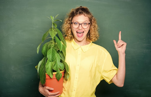 Aluna feliz de educação ambiental com planta no quadro-negro professora mulher de óculos na aula de biologia escola natureza estudo árvore do conhecimento escola aprendendo ecologia transplante flores