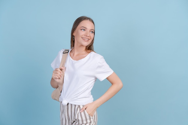 Aluna feliz em roupas casuais leves fica sorrindo em fundo azul