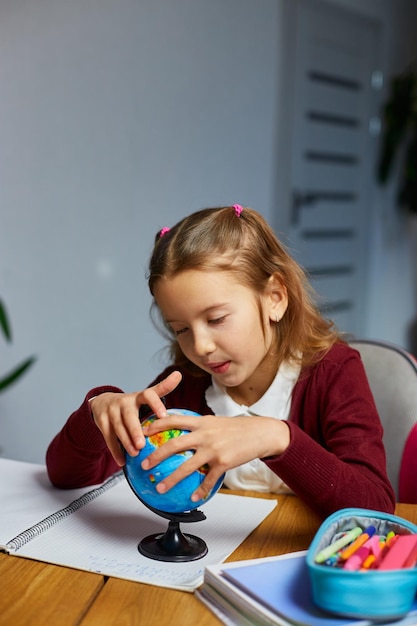 Aluna feliz no local de trabalho estudando o globo na sala de aula