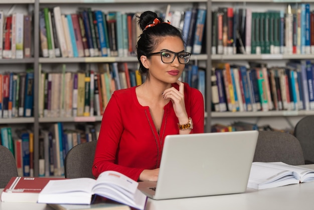 Aluna feliz trabalhando com laptop na biblioteca