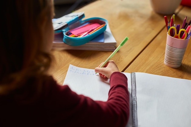 Aluna focada senta-se na mesa fazendo lição de casa caligrafia homeschooling