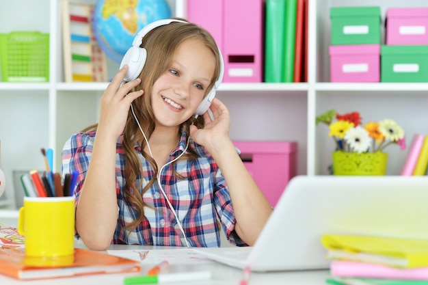 Aluna fofa em fones de ouvido com laptop na aula