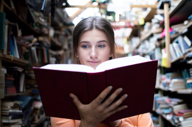 Foto aluna lê um livro em uma biblioteca antiga