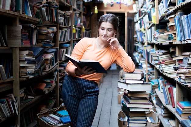 Aluna lê um livro na biblioteca uma mulher gosta de ler muito ela está procurando literatura