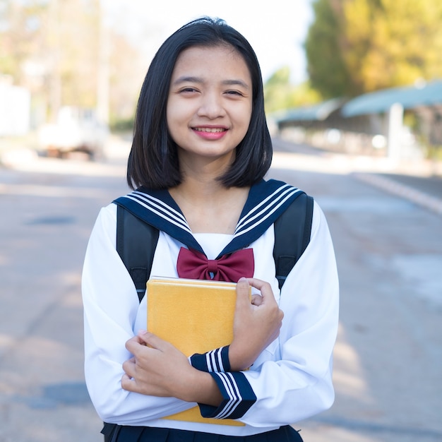 Foto aluna linda segurando livro na escola