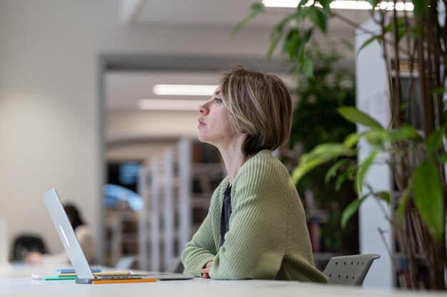 Aluna madura fazendo uma pausa no aprendizado on-line enquanto está sentado na biblioteca da universidade