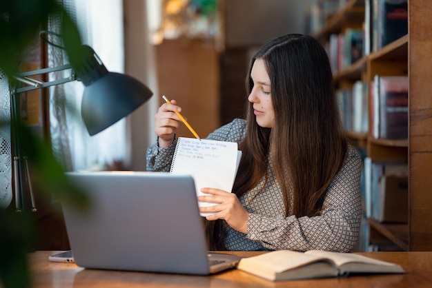 Aluna morena tendo aula on-line demonstrando algumas informações escritas para seu professor e colegas Conceito de obtenção de conhecimento, educação, tecnologias modernas e vida de estudantes