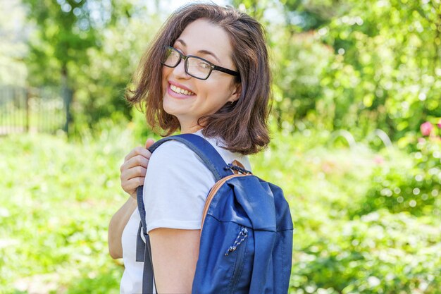 Aluna positiva linda feliz em óculos com mochila sorrindo