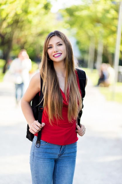 Aluna segurando um livro ao ar livre no parque e sorrindo