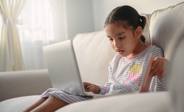 Aluna sentada à mesa, escrevendo a lição de casa. Adolescente que usa o laptop para estudar. Novo normal. Distanciamento social.