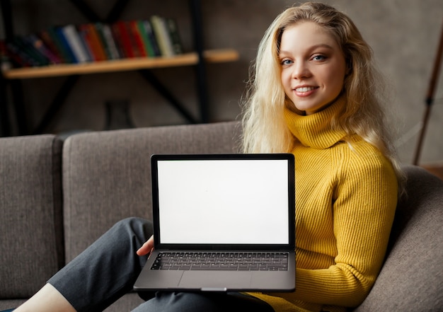 Aluna sentada no sofá segurando laptop olhando a simulação de tela, aprendizagem on-line no pc, e-learning. vista de perto