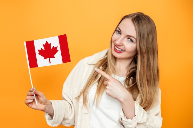 Aluna sorrindo e apontando o dedo para a pequena bandeira do canadá