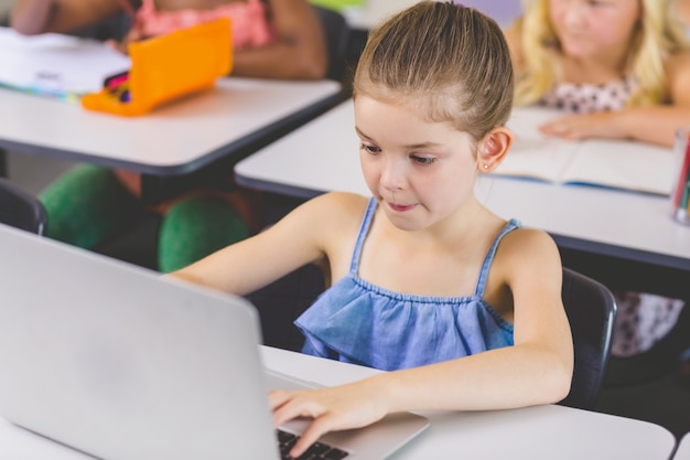 Aluna usando o laptop na sala de aula