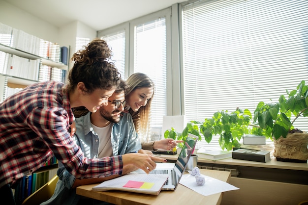 Alunas, mostrando ao colega o que aprender para o exame. no laptop de mesa e papéis.