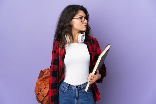 Foto aluno adolescente isolado em um fundo roxo, olhando para o lado