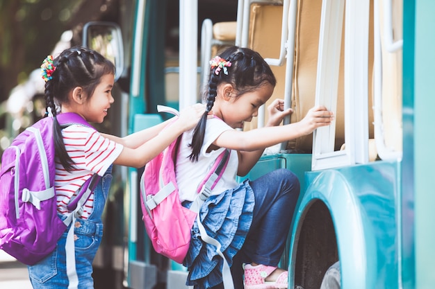 Aluno asiático crianças com mochila segurando a mão e ir para a escola com o ônibus escolar juntos