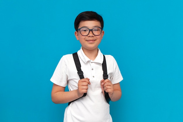Aluno asiático de óculos com mochila sorri em fundo azul criança coreana volta para a escola