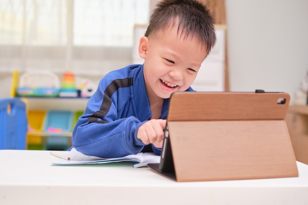 Aluno asiático usando um laptop e estudando a lição de casa durante a aula on-line em casa