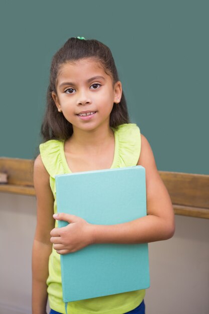 Foto aluno bonito sorrindo na câmera em sala de aula segurando bloco de notas