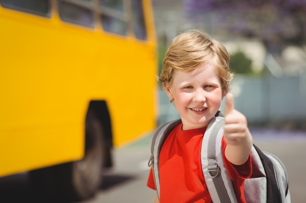 Aluno bonito sorrindo na câmera pelo ônibus escolar