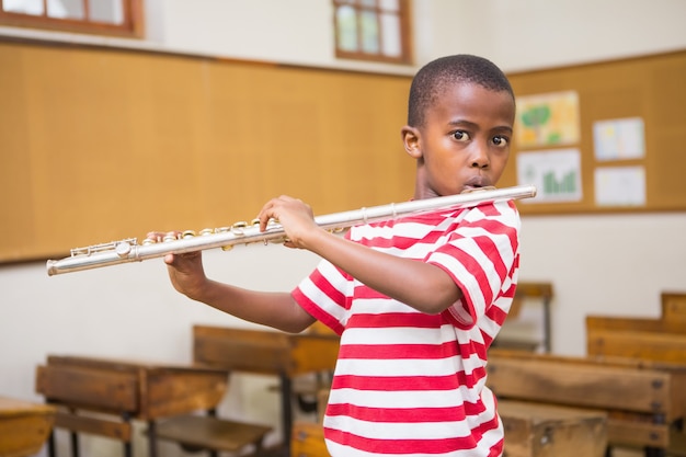 Aluno bonito tocando flauta em sala de aula