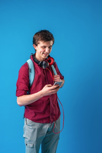 Aluno com mochila, celular e fones de ouvido se comunica via internet