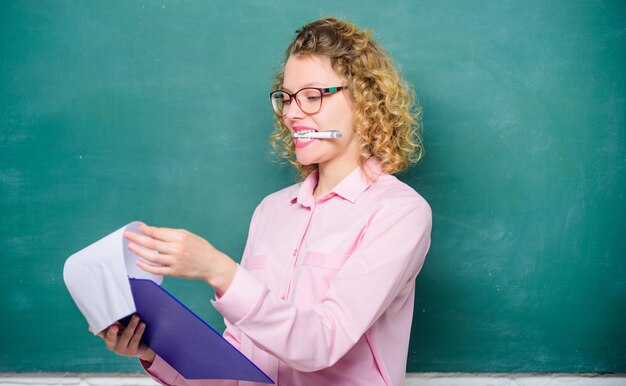 Aluno confiante em óculos no quadro-negro professor de menina no projeto de relatório de aula particular de volta ao professor de redação da escola com pasta de documentos no próximo ano letivo Menina se prepare para os exames