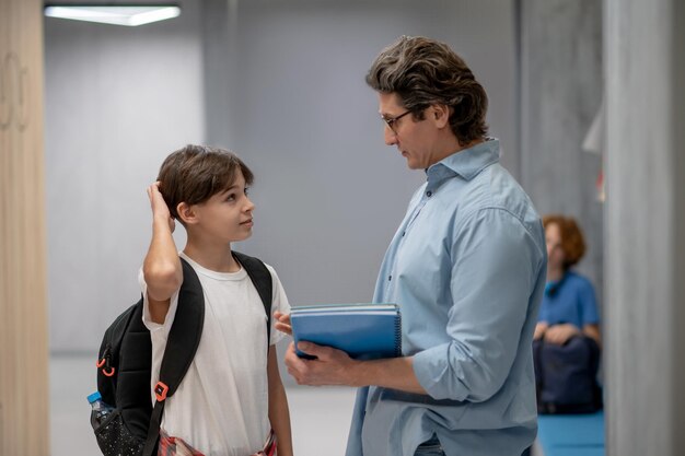 Aluno curioso se comunicando com o professor no corredor