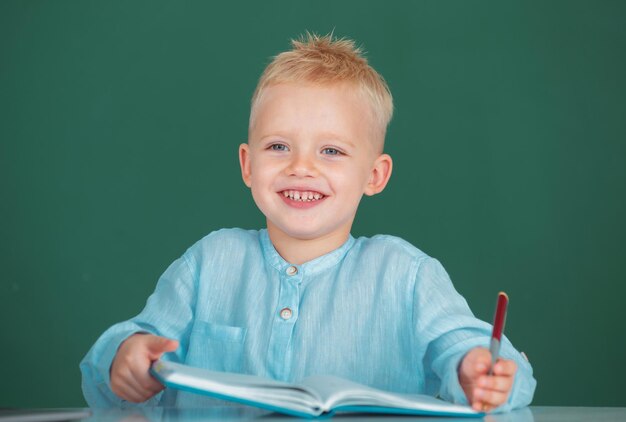 Aluno da escola aprende lição sentado na mesa estudando criança escrevendo no caderno na aula educatio