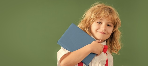 Aluno da escola no espaço da cópia do banner do quadro-negro menino feliz no estudo de gravata borboleta na aula da escola com notebook em setembro