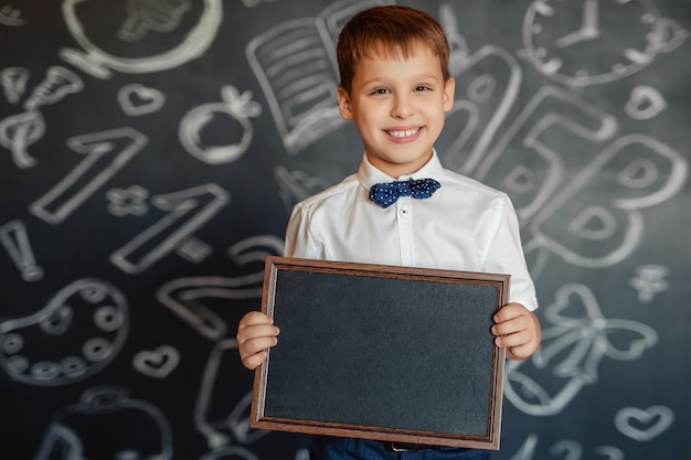 Aluno da escola primária com um quadro negro nas mãos