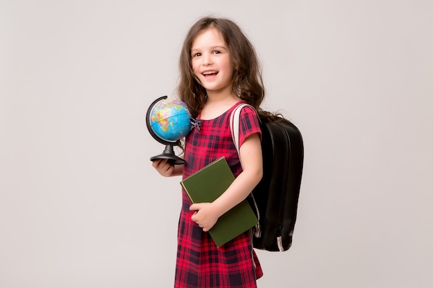 aluno da primeira série com livros e um globo sorrindo