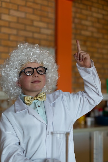 Aluno de escola com peruca branca levantando a mão no laboratório