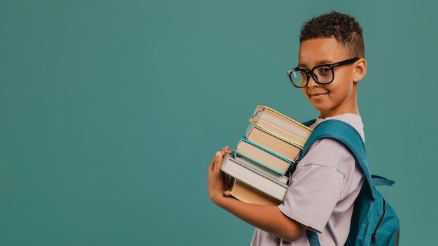 Aluno de escola segurando uma pilha de livros