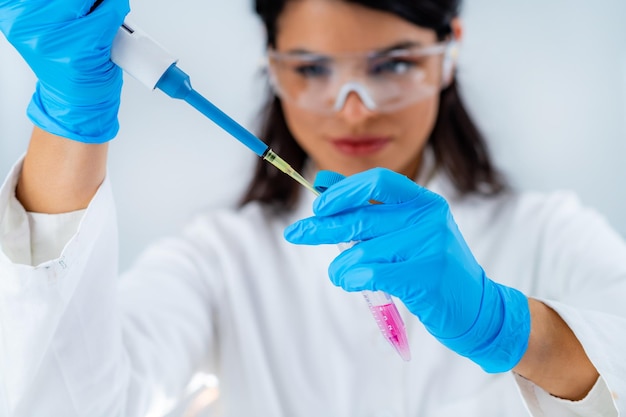 Aluno de jaleco branco trabalhando em laboratório de pesquisa usando micro pipeta e tubo de ensaio