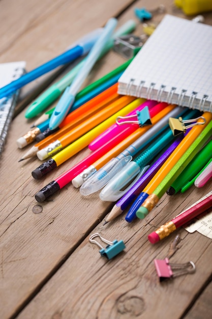 Foto aluno de lápis e canetas com um caderno em uma superfície de madeira